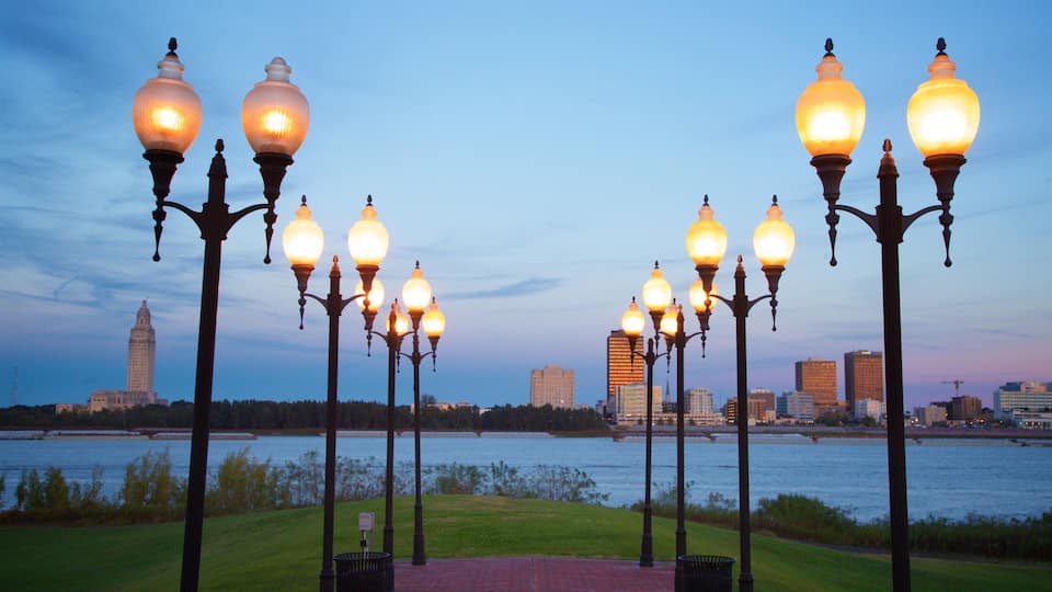 A waterfront promenade with ornate street lamps and a distant view of a city skyline.