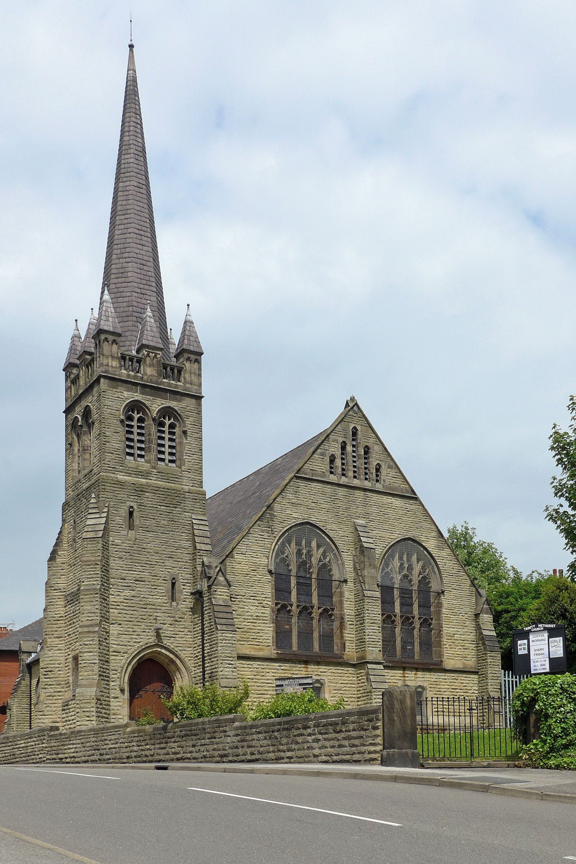 A historic stone church with a tall spire and arched windows.