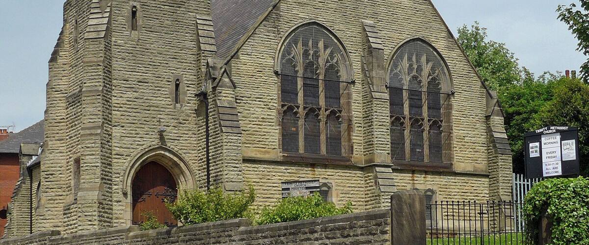 A historic stone church with a tall spire and arched windows.