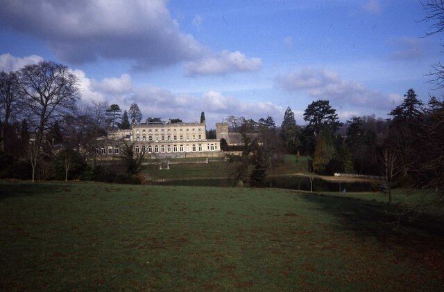 A large, historic building with a symmetrical facade, surrounded by a well-maintained lawn and trees.