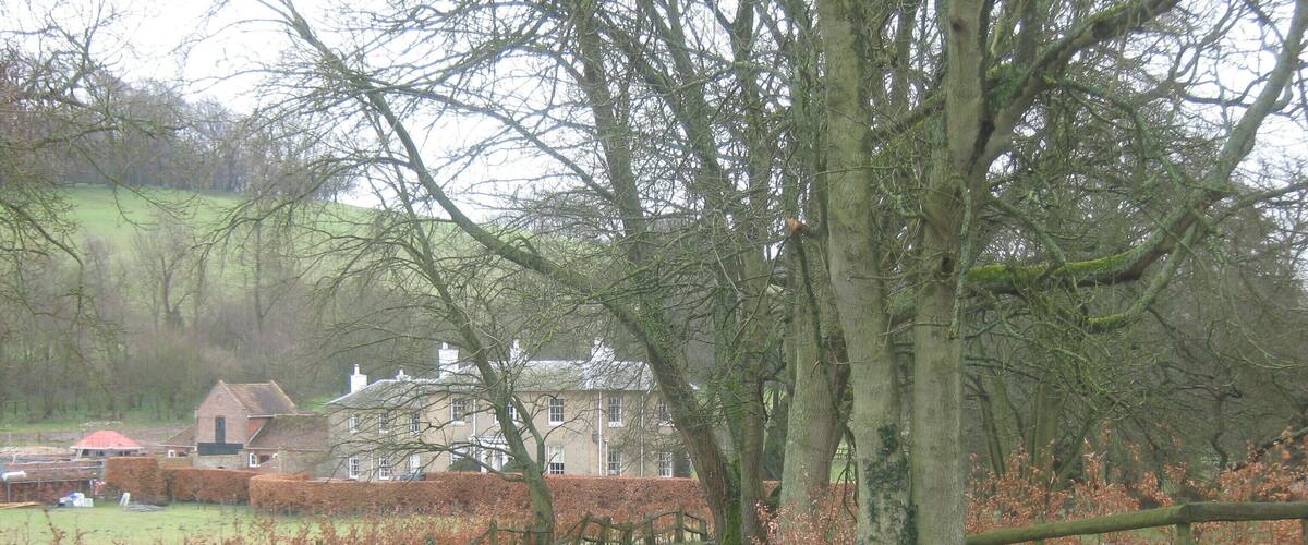 A rural road leading to a property named "The Old Rectory" surrounded by trees and a hedge.