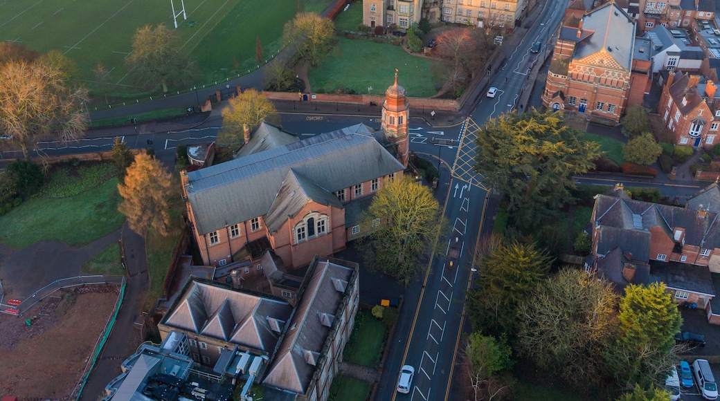 An aerial view of a town with a prominent church, a large green field, and a mix of residential and commercial buildings.