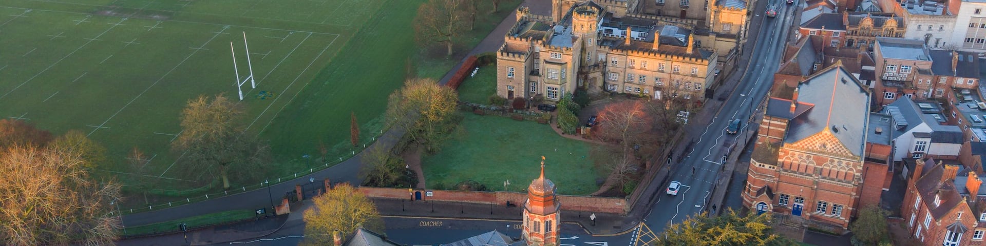 An aerial view of a town with a prominent church, a large green field, and a mix of residential and commercial buildings.