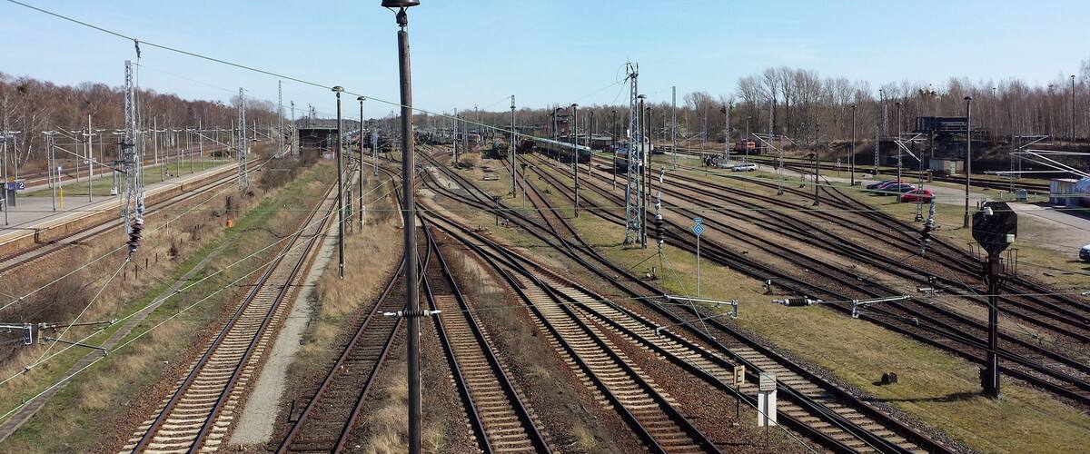 A complex railway yard with multiple tracks and overhead electrical lines.