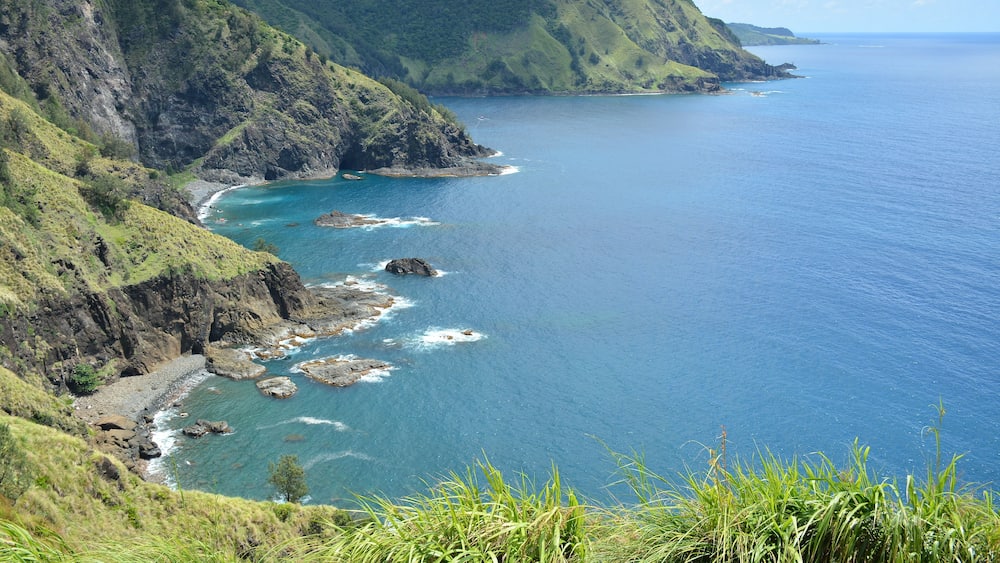 A coastal landscape with green hills and rocky coastline.