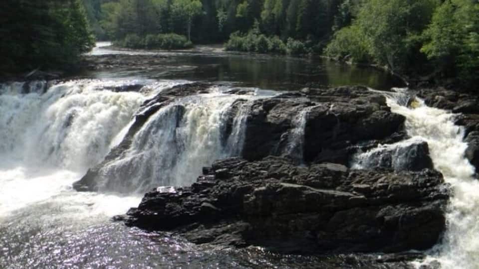 A waterfall cascading over rocks in a forested area.