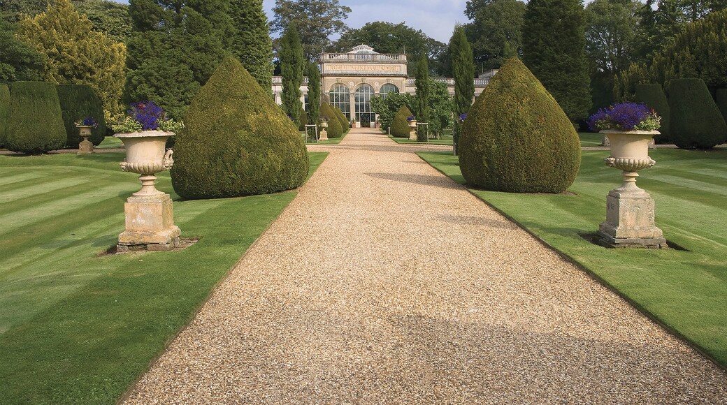 A formal garden with a gravel path leading to a classical building.
