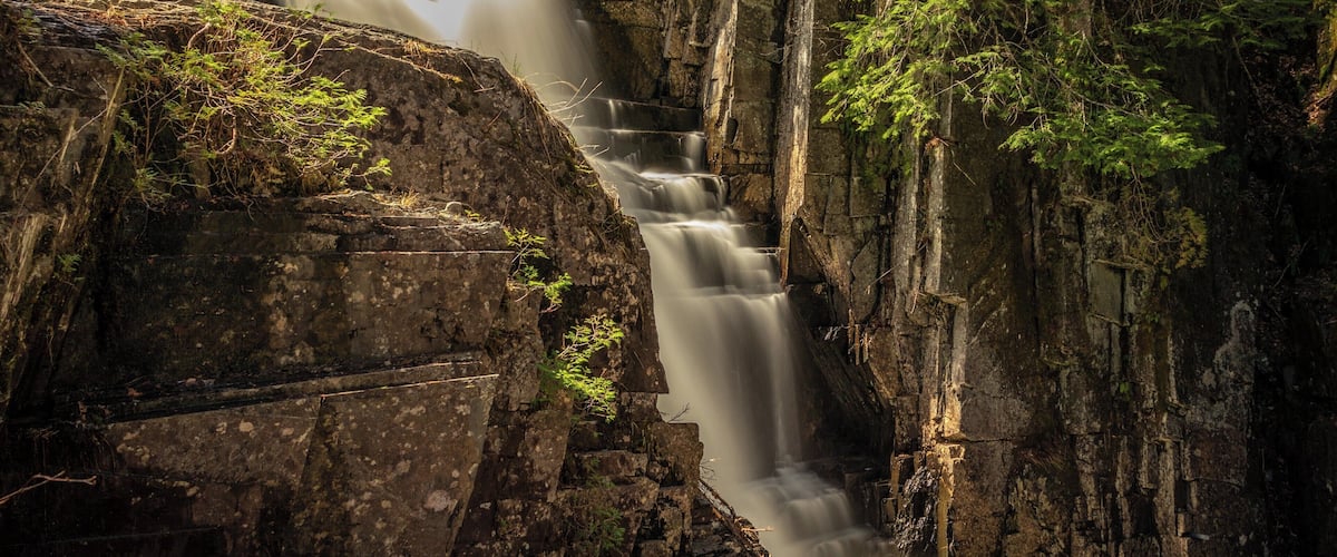 A waterfall cascading down a rocky cliff surrounded by dense forest.