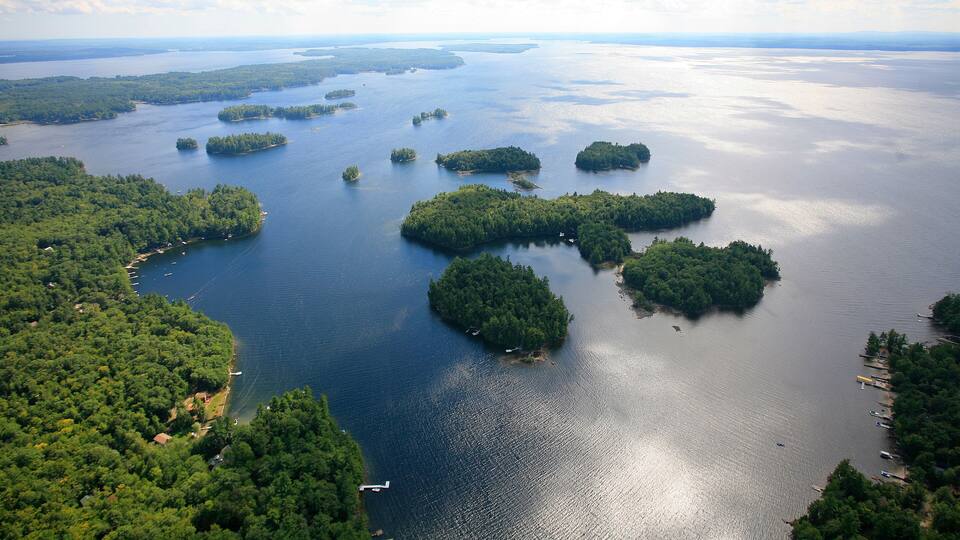 An aerial view of a large body of water with multiple islands surrounded by dense forests.