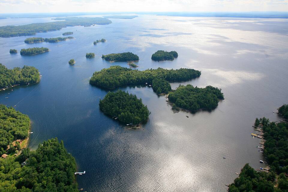 An aerial view of a large body of water with multiple islands surrounded by dense forests.
