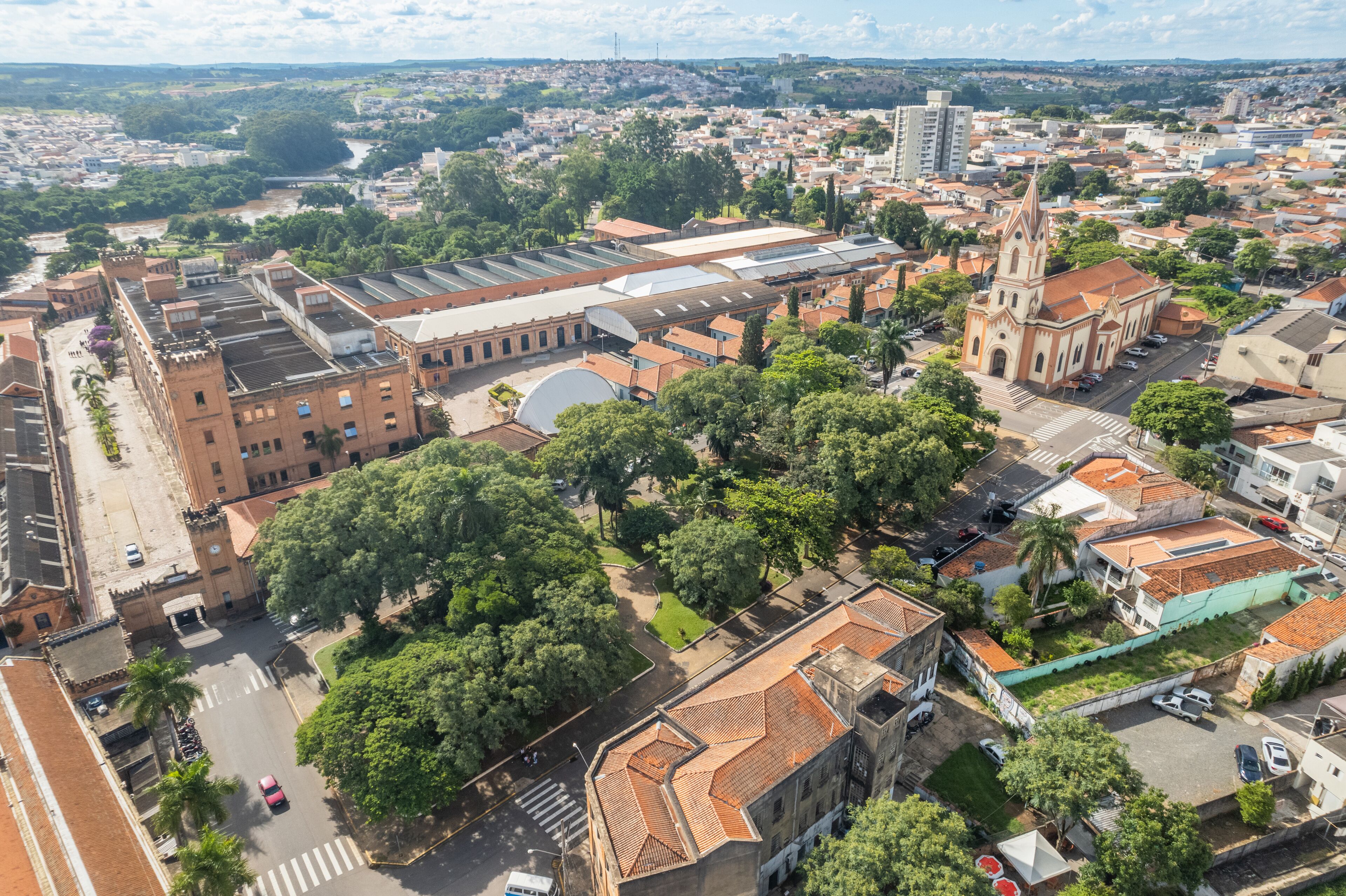 An aerial view of a city with a prominent church, a large industrial building, and surrounding residential areas.