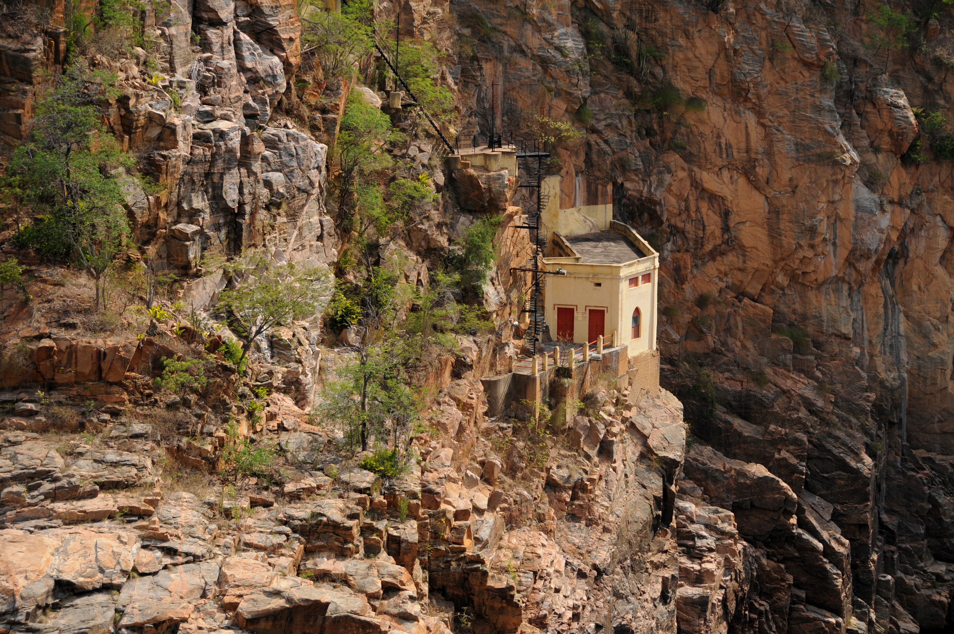A small building perched on a rocky cliff with a steep drop-off.