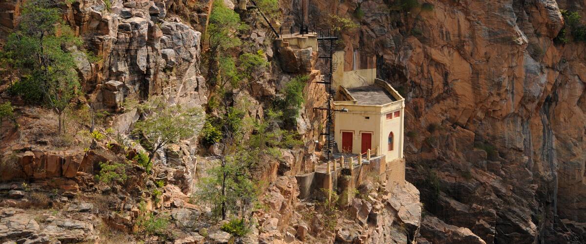 A small building perched on a rocky cliff with a steep drop-off.