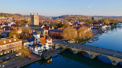 A riverside town with historic buildings, a prominent tower, and a bridge.