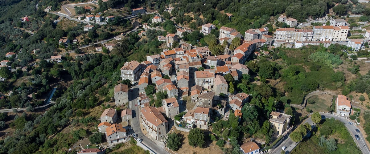 Aerial view of the village of Sainte Lucie de Tallano in the mountains of Southern Corsica, France - Round shaped medieval village with old houses surrounded by pine forests