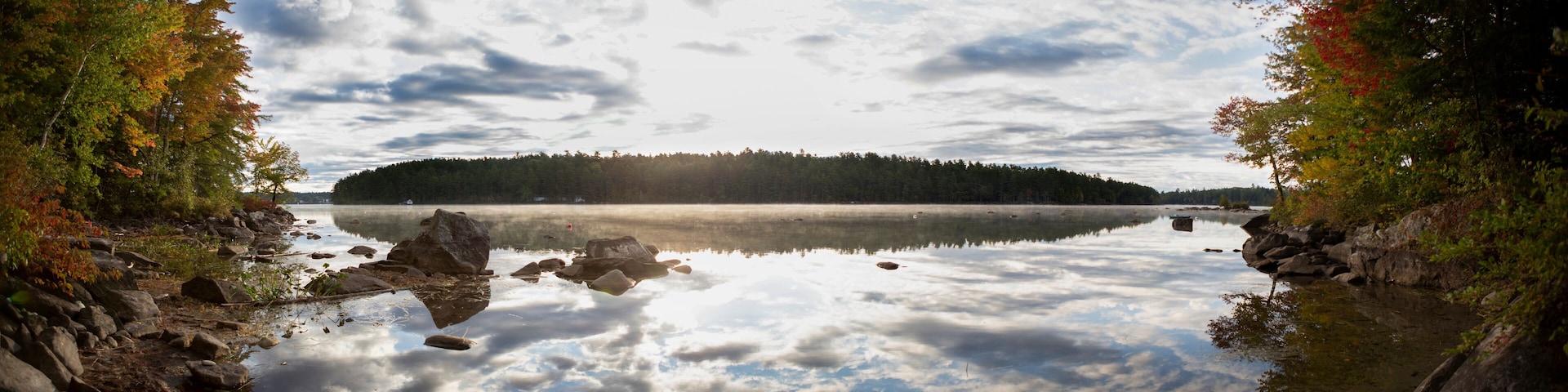 A calm lake surrounded by rocky shores and dense forest.