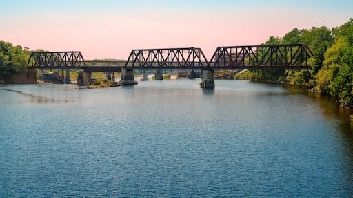Rustic railway tracks and the historic Waterville–Winslow Railroad Bridge span the Kennebec River in Waterville, Maine, USA—a steel truss structure built around natural rock formations