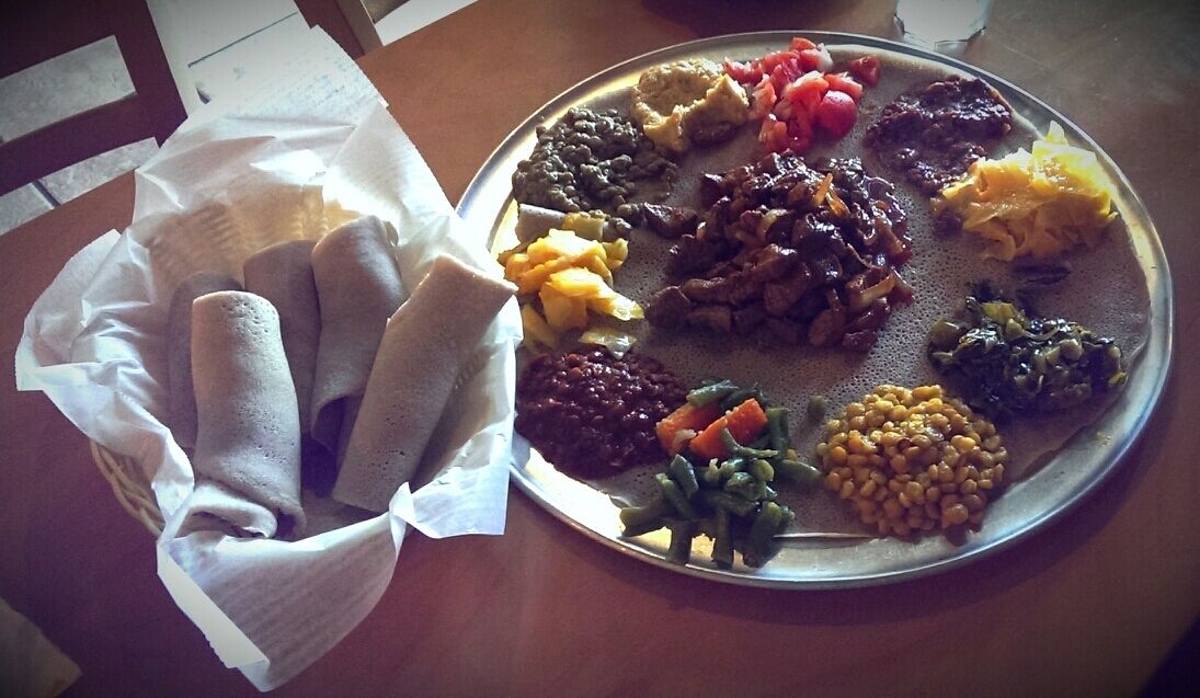 A plate of Ethiopian cuisine with injera, lentils, and vegetables.