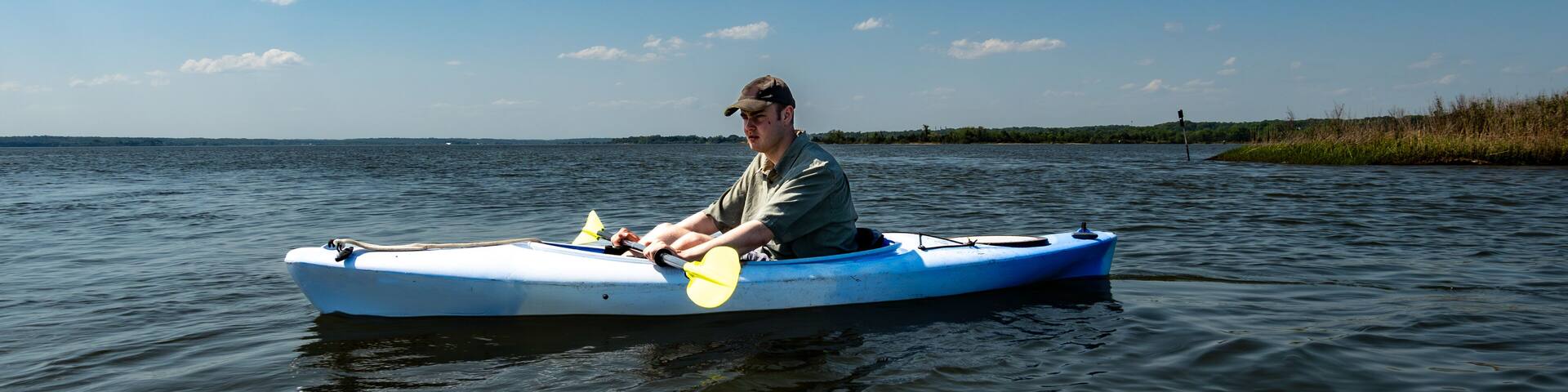 Broomes Island, Maryland USA A young man kayaks on the Patuxent River on a sunny day.