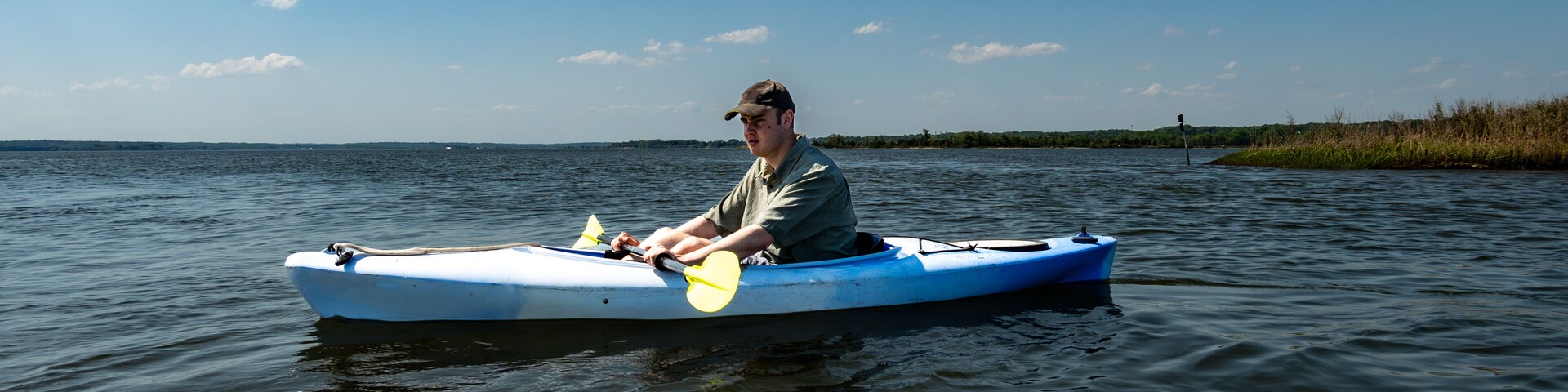Broomes Island, Maryland USA A young man kayaks on the Patuxent River on a sunny day.