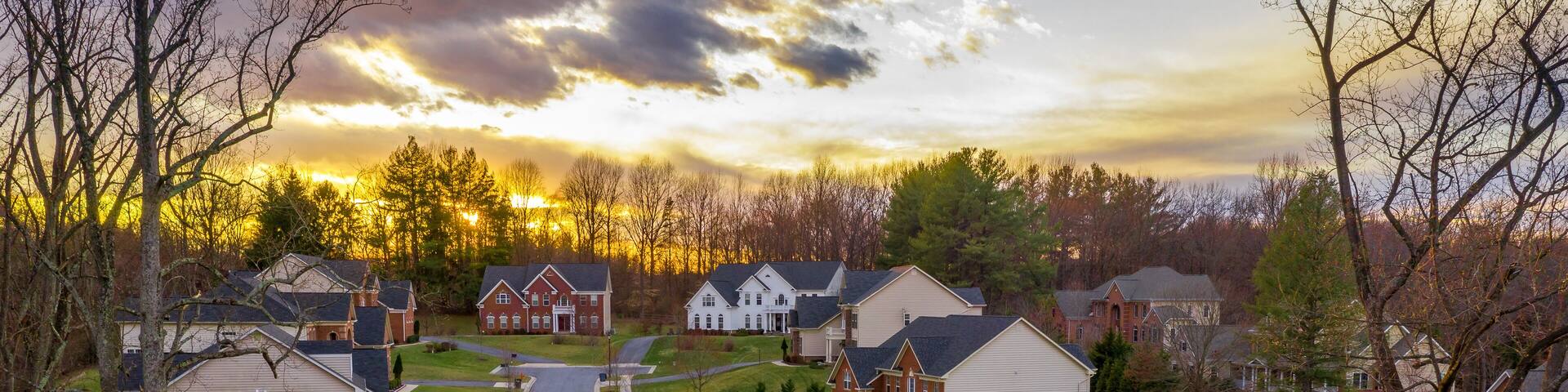 Aerial panorama of modern upper middle class single family homes neighborhood street American real estate in a new construction in Maryland USA sunset