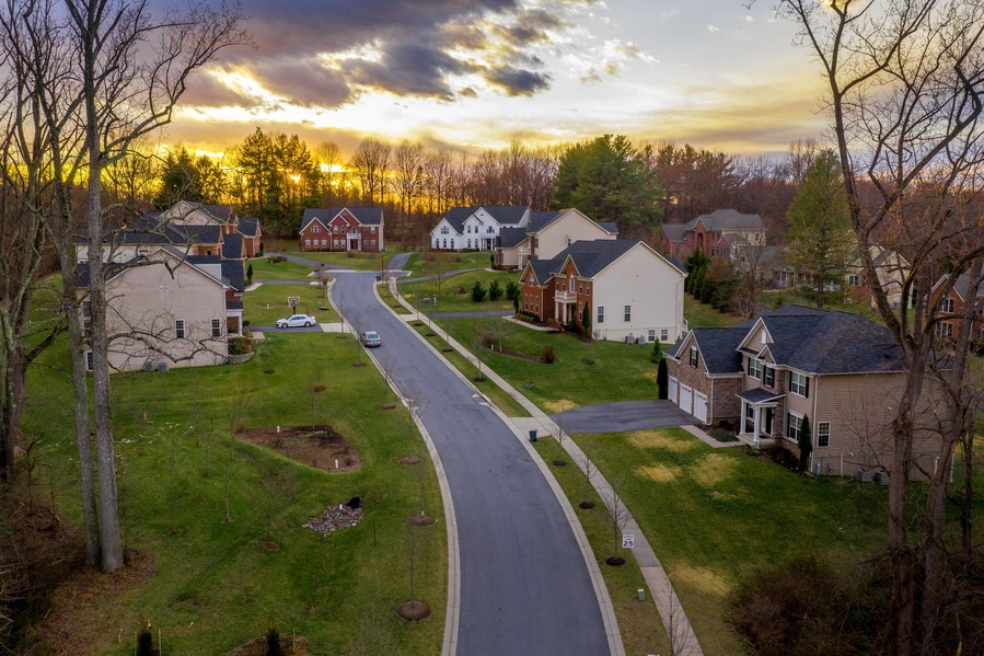Aerial panorama of modern upper middle class single family homes neighborhood street American real estate in a new construction in Maryland USA sunset