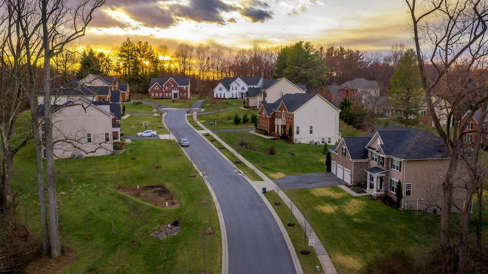 A suburban neighborhood with houses, a curved road, and a sunset.