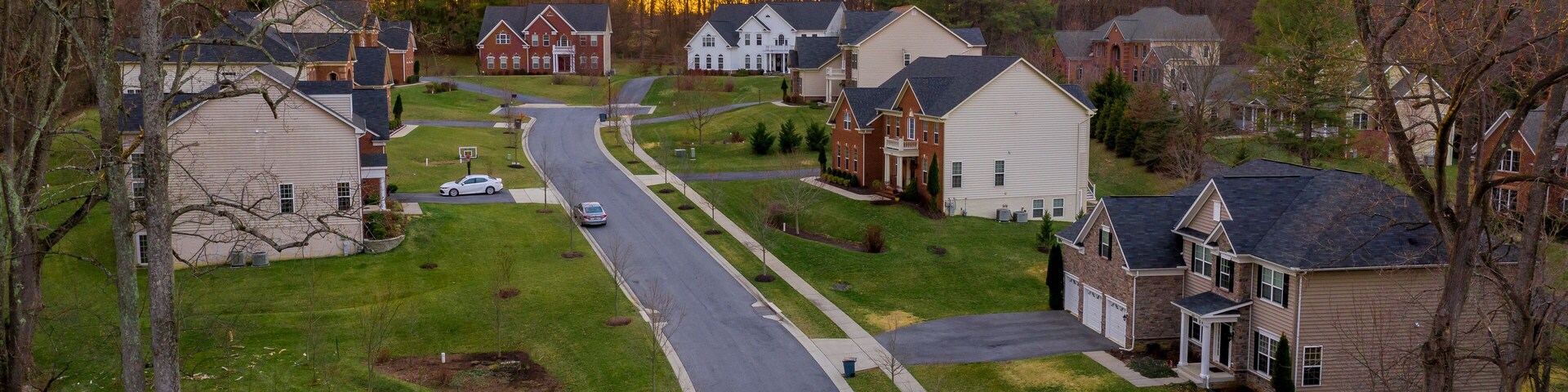 Aerial panorama of modern upper middle class single family homes neighborhood street American real estate in a new construction in Maryland USA sunset