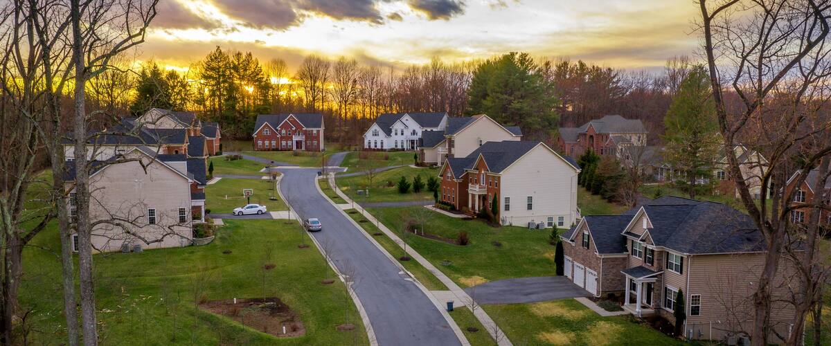 A suburban neighborhood with houses, a curved road, and a sunset.