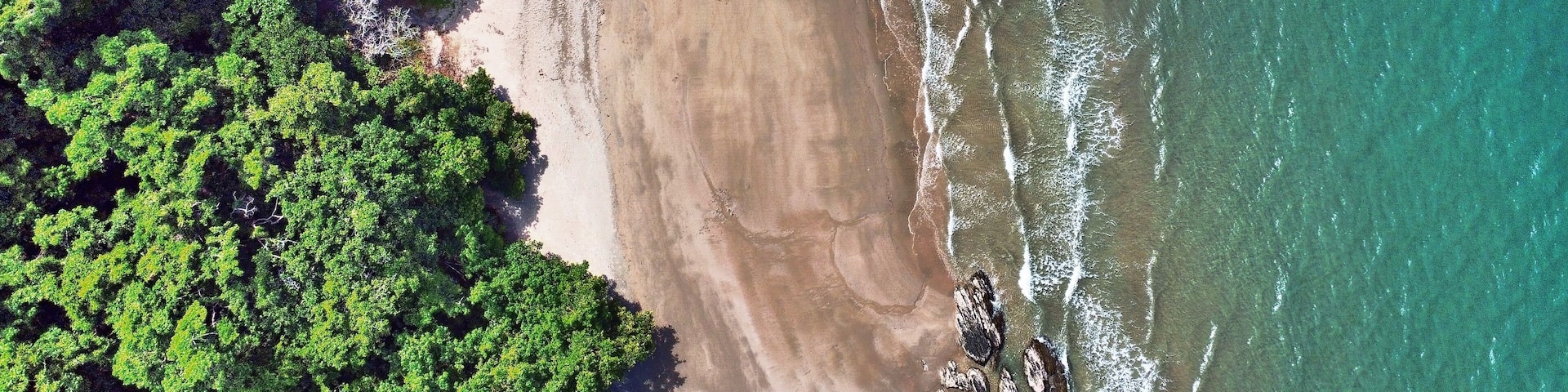 Downward drone shot of Etty beach ocean and rainforest