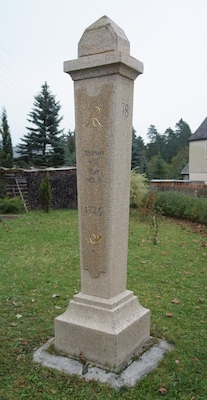 Um monumento de pedra com inscrições, cercado por grama e árvores.