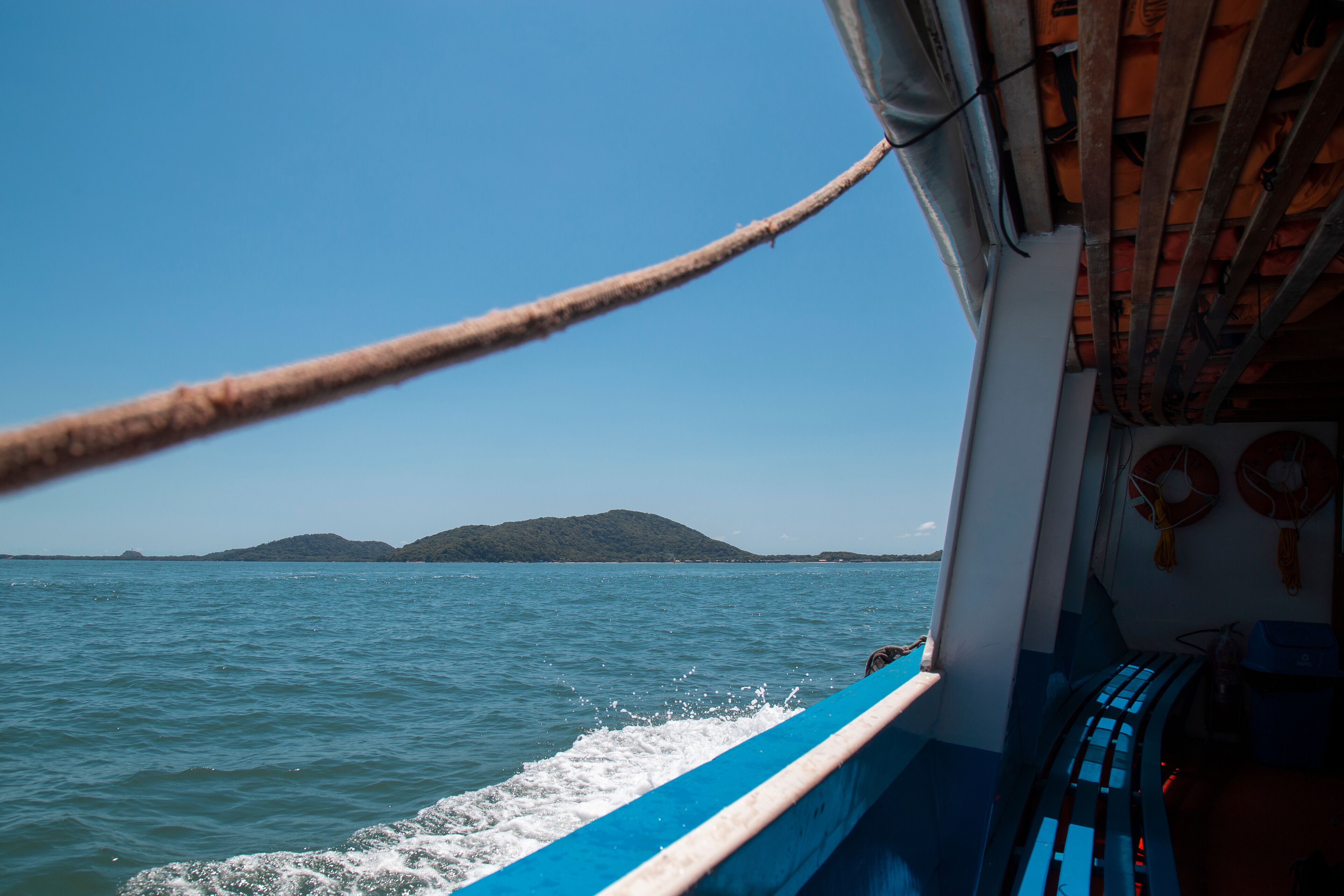 A boat on a calm sea with a clear sky and distant land.