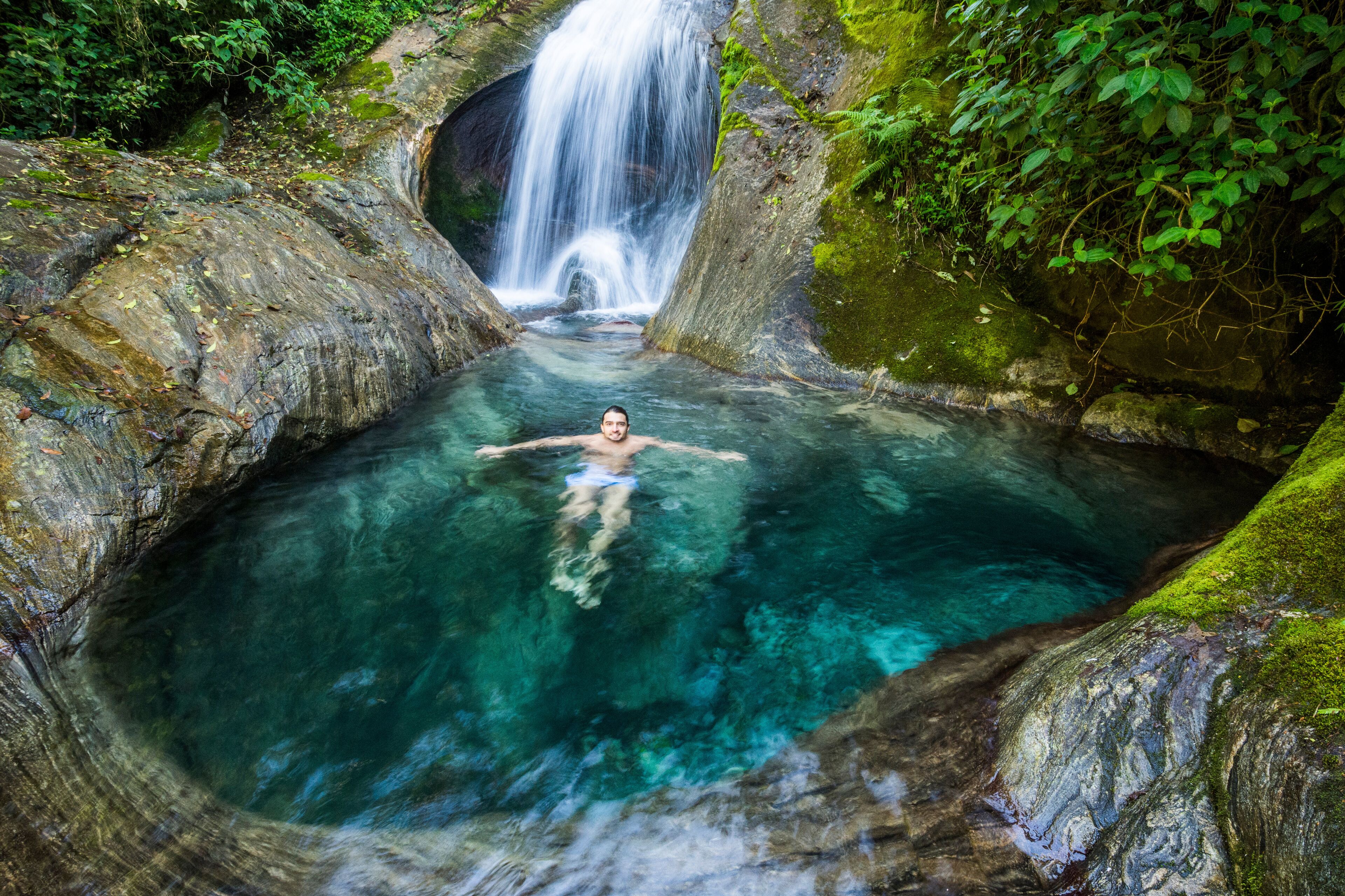 Scenery with man swimming in Atlantic Rainforest river, Serrinha do Alambari, Rio de Janeiro State, Brazil
