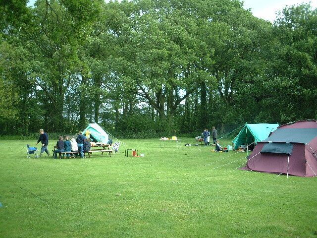 A grassy field with tents and people gathered around.