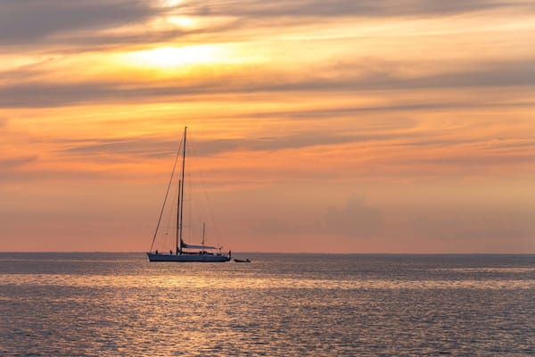 Un voilier sur des eaux calmes, au coucher du soleil.