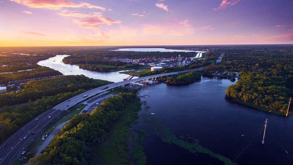 A river with a bridge, a highway, and industrial buildings.
