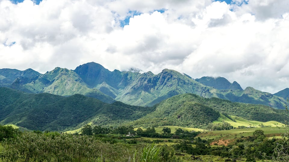 A mountainous landscape with lush green hills and a church in the valley.