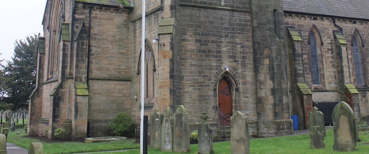 A historic church with a tall spire and a graveyard in front.