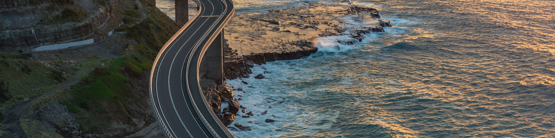 A coastal road curving along a cliffside with the ocean in the background.