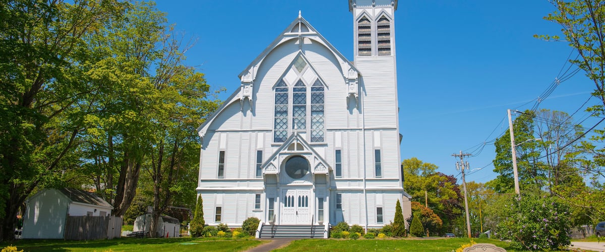 A white church with a steeple and a large arched window.
