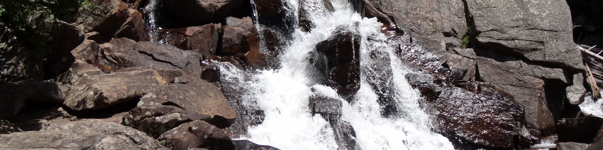 Waterfall cascading over a rocky cliff in front of lush forest in Granby.