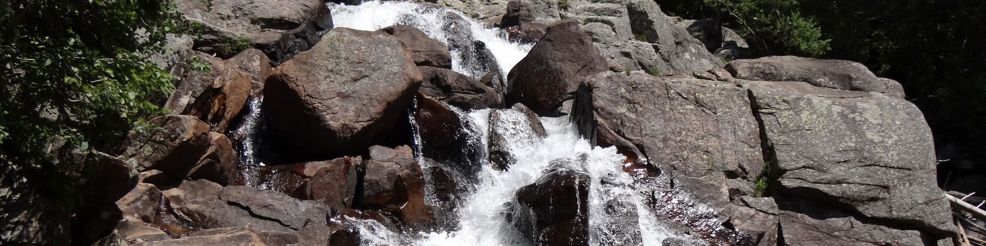 Waterfall cascading over a rocky cliff in front of lush forest in Granby.