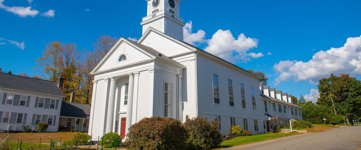 A white church with a steeple and a clock tower.
