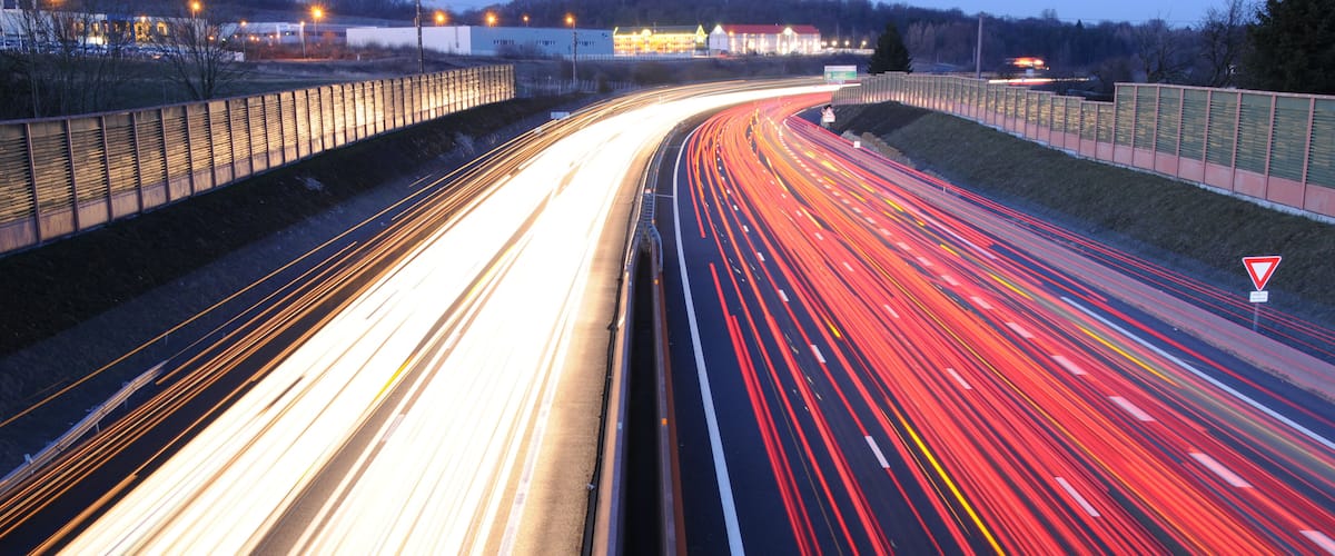 A multi-lane highway with light trails from vehicles at dusk.