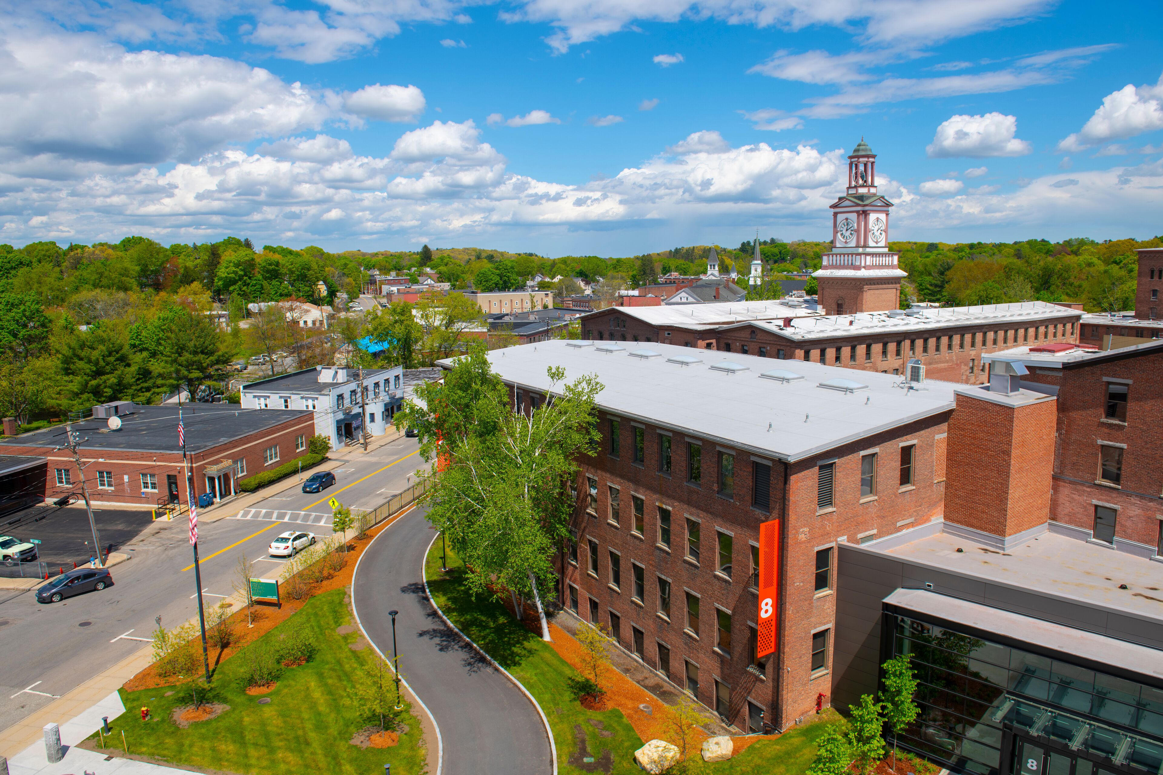A town with a prominent clock tower, a curved road, and a mix of brick and modern buildings.