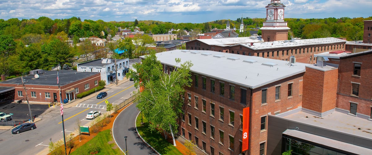 A town with a prominent clock tower, a curved road, and a mix of brick and modern buildings.