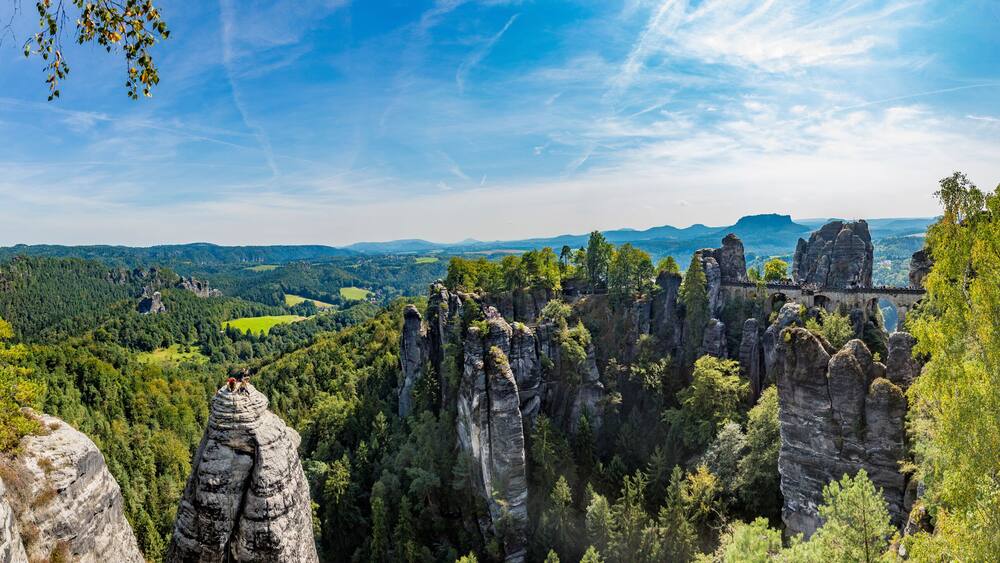 A landscape with rock formations, trees, and a distant view of a valley.