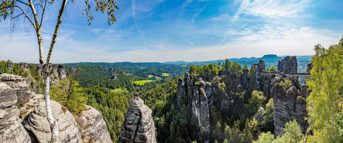A landscape with rock formations, trees, and a distant view of a valley.