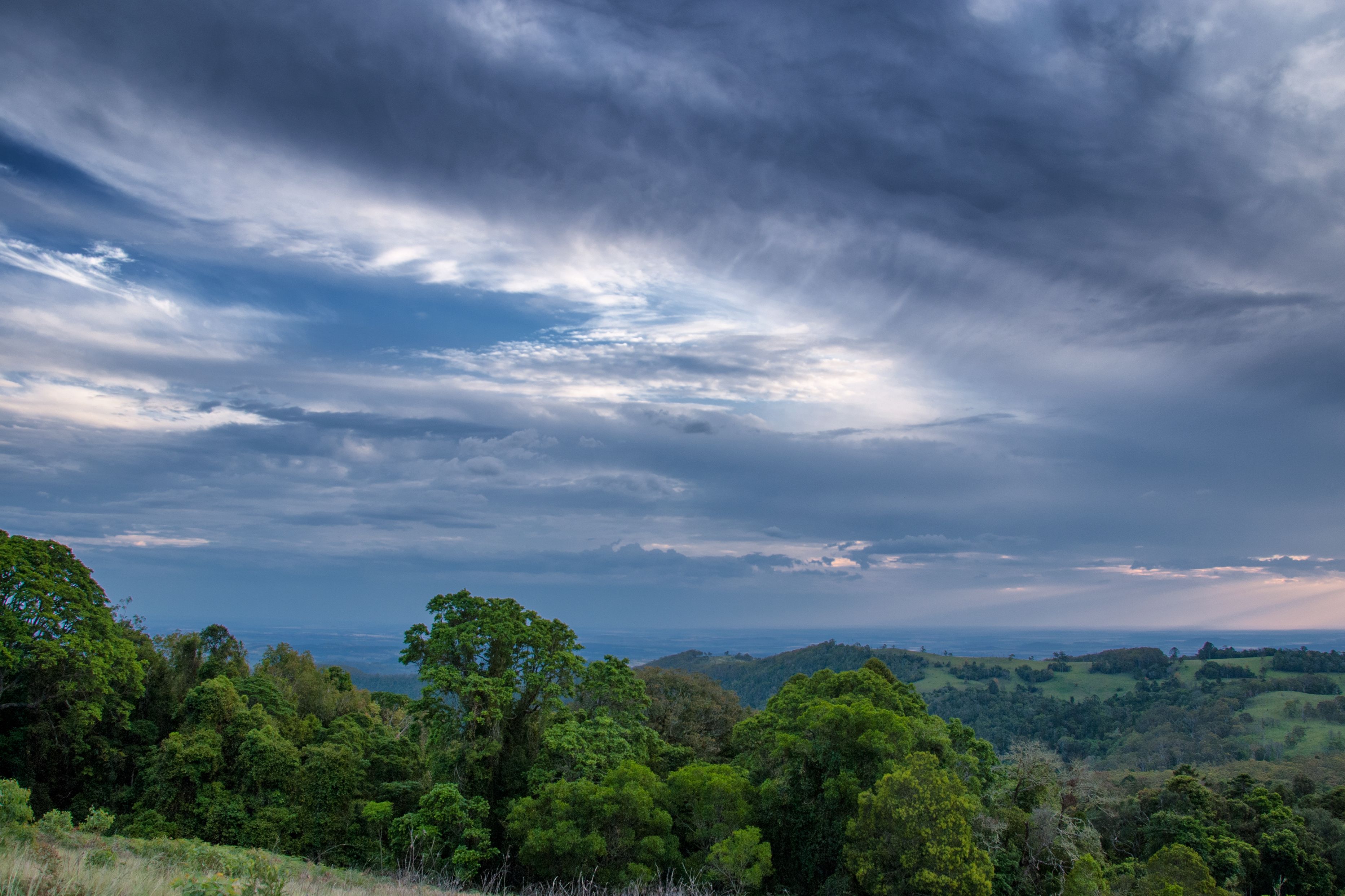 Un paysage caractérisé par une végétation luxuriante, des collines ondoyantes et un ciel nuageux.