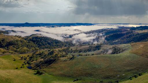 Aerial view of low-level clouds in a large green valley in regional Australia